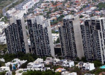 Bird's-eye View of a Cluster of Tall Concrete Apartment Towers Amid a Dense Hillside Cityscape with Low-rise Houses Surrounding Them - Los Industriales