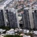 Bird's-eye View of a Cluster of Tall Concrete Apartment Towers Amid a Dense Hillside Cityscape with Low-rise Houses Surrounding Them - Los Industriales